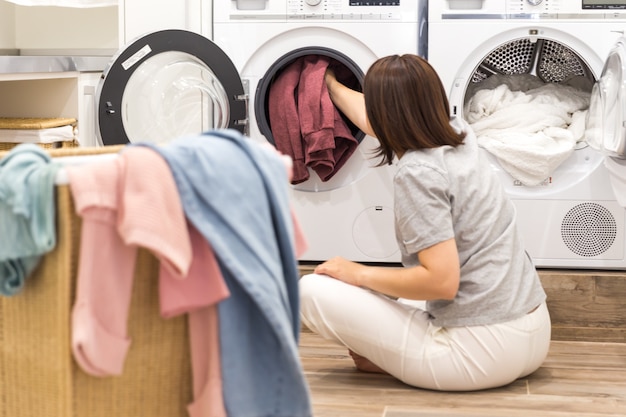 Vrouw die Vuile Kleren in Wasmachine voor Was in moderne Bijkeuken laden