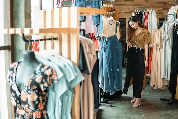 Vrouw die wat kleren in de manieropslag bekijkt