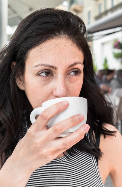 Foto vrouw die wegkijkt terwijl ze koffie drinkt