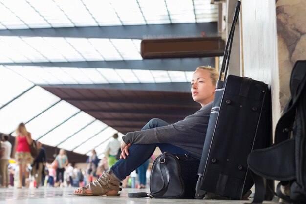 Foto vrouw die wegkijkt terwijl ze op de luchthaven zit