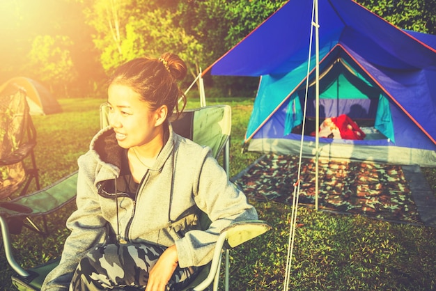 Vrouw die wegkijkt terwijl ze op een stoel bij een tent zit