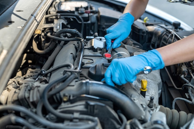 Vrouw die werkt als monteur in een autoservice en het chassis van een auto repareert met een sleutel