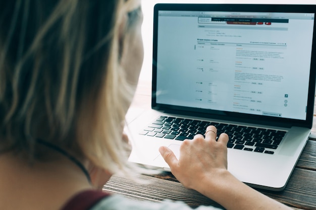 Vrouw die werkt met een laptop die op het houten bureau is geplaatst