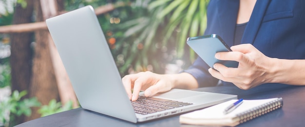 Foto vrouw die werkt met een laptopcomputer en een mobiele telefoon gebruikt op kantoor