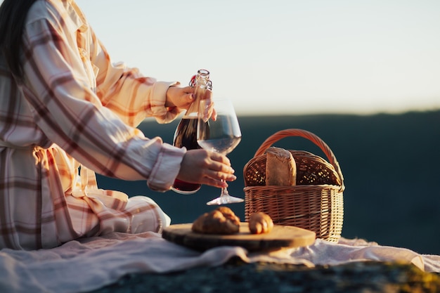 vrouw die wijn schenkt terwijl ze aan het picknicken is