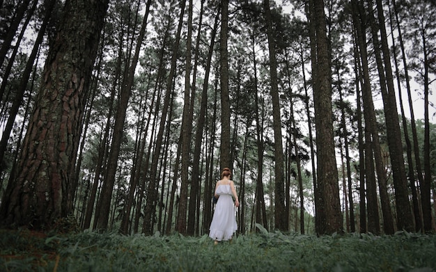 Vrouw die witte kleding draagt ​​die in het bos loopt.