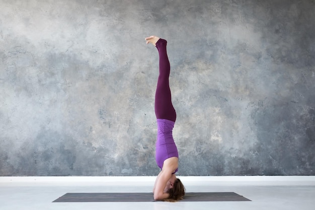 Vrouw die yoga beoefent die in salamba sirsasana staat, oefening hoofdstand pose