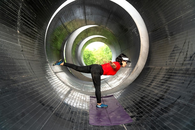 Foto vrouw die yoga beoefent in een metalen tunnel foto