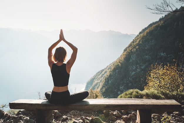 Vrouw die yoga beoefent op de natuur jonge vrouw mediteert op de achtergrond van bergen