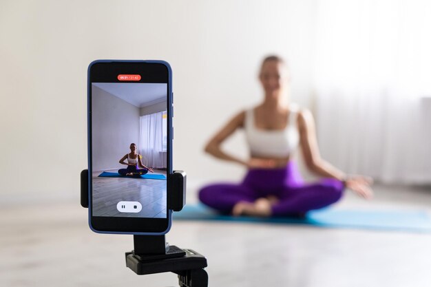 Vrouw die yoga beoefent poseert voor telefoon camera sport blogger leraar yoga online