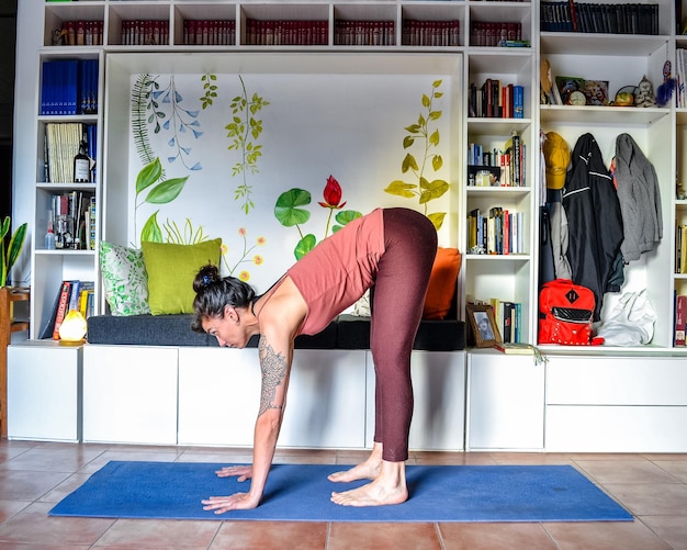 vrouw die yoga beoefent thuis houdingen ardha uttanasana