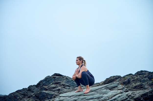 vrouw die yoga beoefent voor de zee