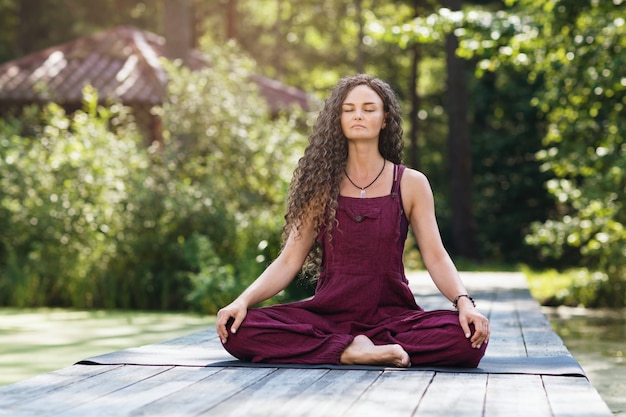 Vrouw die yoga beoefent, zittend op een mat in een lotushouding, is bezig met meditatie