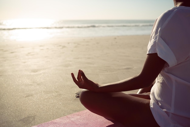 Foto vrouw die yoga doet op het strand