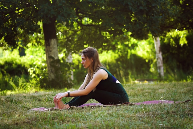 Vrouw die yoga in het de zomerpark doet