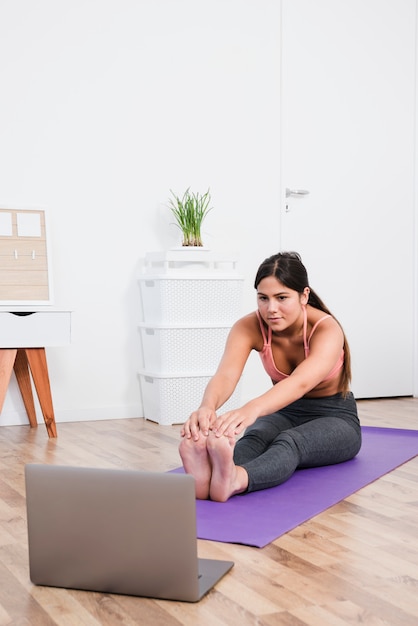 Foto vrouw die yoga met laptop doet