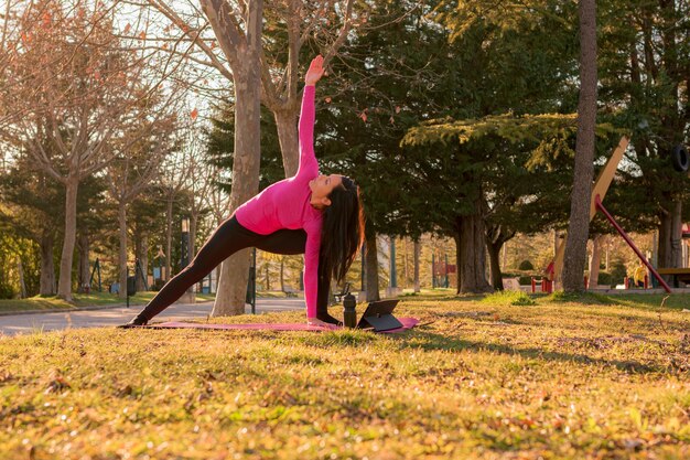 Vrouw die yoga-oefeningen uitvoert in een park bij zonsondergang