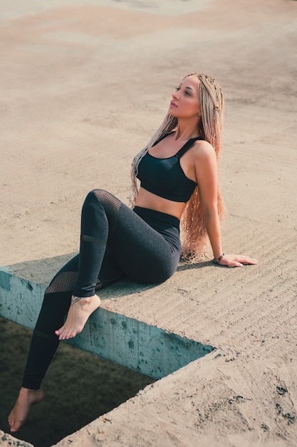 Vrouw die yoga op het dak van een wolkenkrabber in grote stad doet.