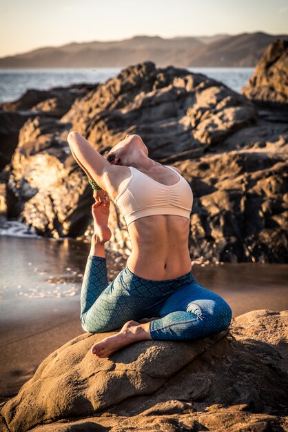 Vrouw die yoga op het strand doet