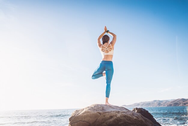 Vrouw die yoga op het strand doet