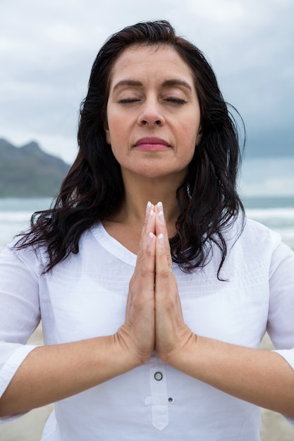 Vrouw die yoga op strand uitvoert