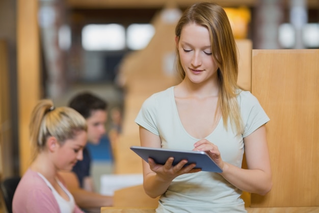 Vrouw die zich houdend een tabletpc bij de bibliotheek bevindt