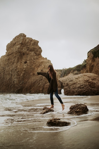 Vrouw die zich op een rots bij het strand bevindt