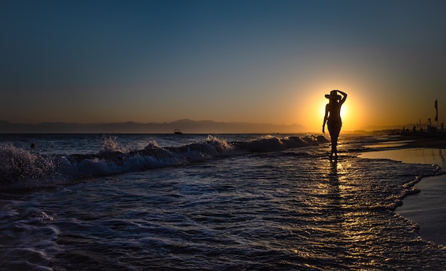 Vrouw die zich op een zonsondergang in oceaangolven bevindt