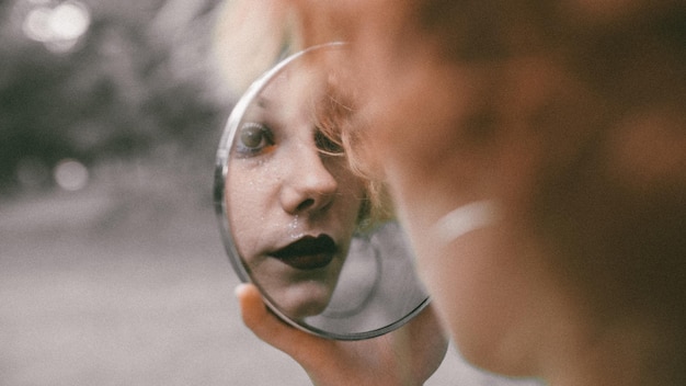 Vrouw die zich reflecteert in de spiegel