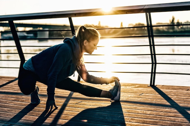 Vrouw die zich strekt na een training buiten bij zonsondergang