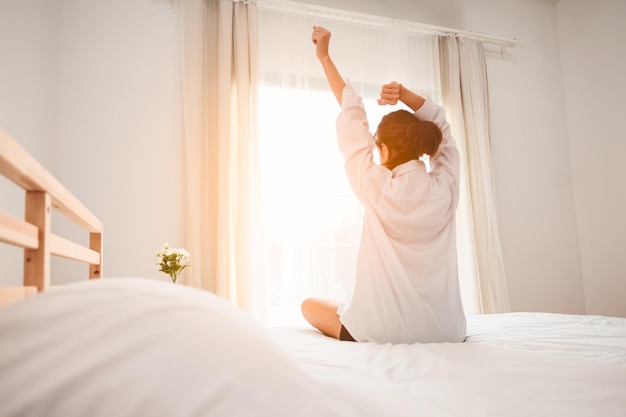 Vrouw die zich uitstrekt in bed na het wakker worden