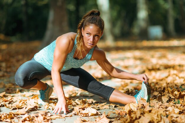 Vrouw die zich uitstrekt in het park in de herfst