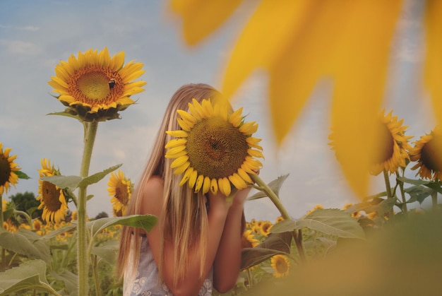 Vrouw die zich verbergt achter zonnebloem op de boerderij