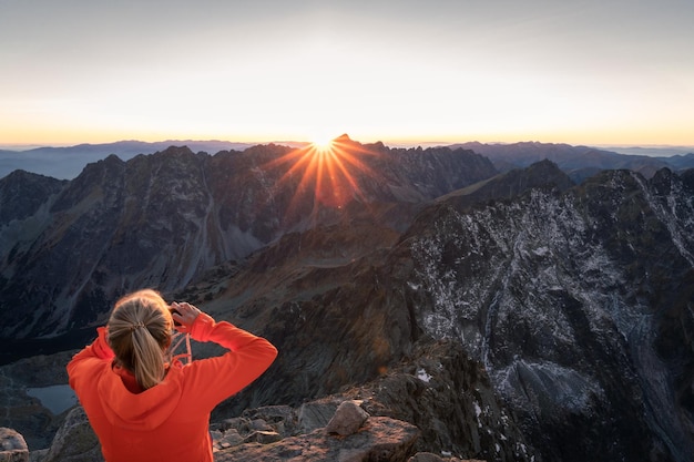 Vrouw die zonsondergang fotografeert in een alpine omgeving, omringd door rotsachtige bergen en toppen in europa