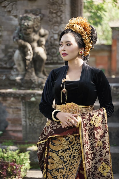 Vrouw die zwarte kebaya draagt met een standbeeld op de achtergrond