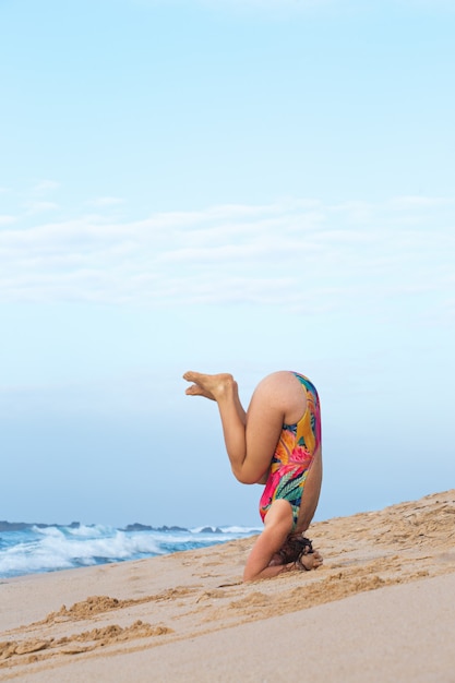 Vrouw doet een handstand aan de kust van de oceaan