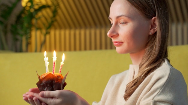 Vrouw doet een wens, blaast de kaarsjes op een verjaardagstaart uit en lacht