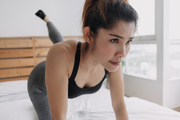 Vrouw doet glute kickback workout in haar slaapkamer appartement