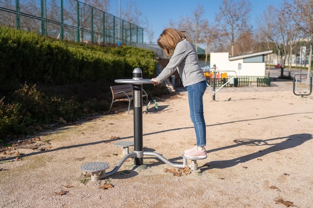 Vrouw doet gymnastiek in een apparaat in een openbaar park voor de verbetering van fysieke vorm en gezondheid