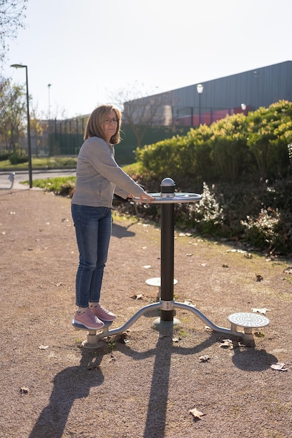 Vrouw doet gymnastiek in een apparaat in een openbaar park voor de verbetering van fysieke vorm en gezondheid