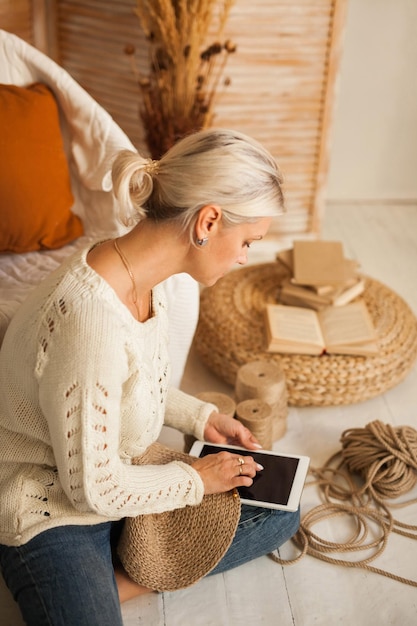 Vrouw doet handwerkbreien van jute met een laptop in haar handen