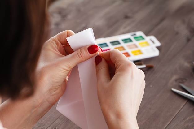 Vrouw doet origami, buigt vel papier voor figuur