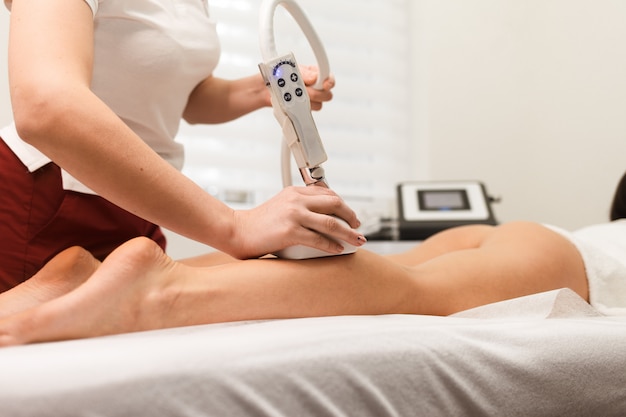 Vrouw doet vacuüm anti-cellulitis massage op haar benen. vacuümmassage-apparaat