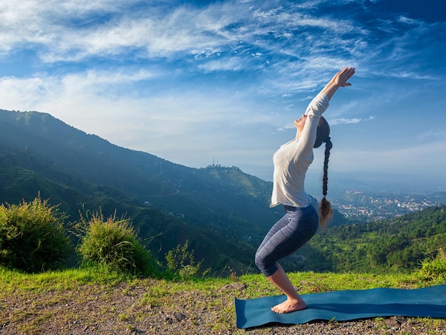 Vrouw doet yoga asana Utkatasana buitenshuis