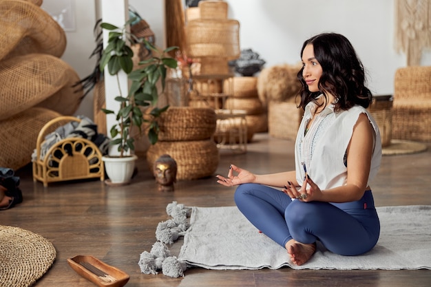 Vrouw doet yoga en meditatieve beoefening in Bali-stijl ingerichte kamer