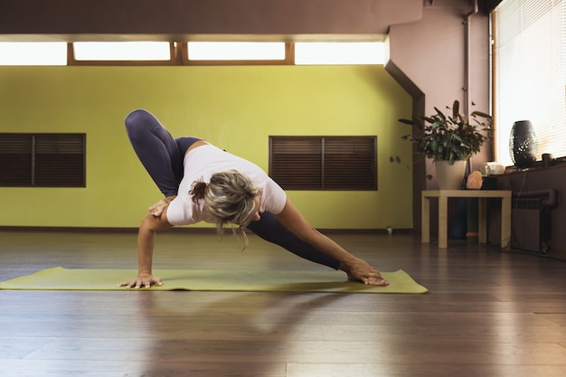 Vrouw doet yoga in studio die op mat staat