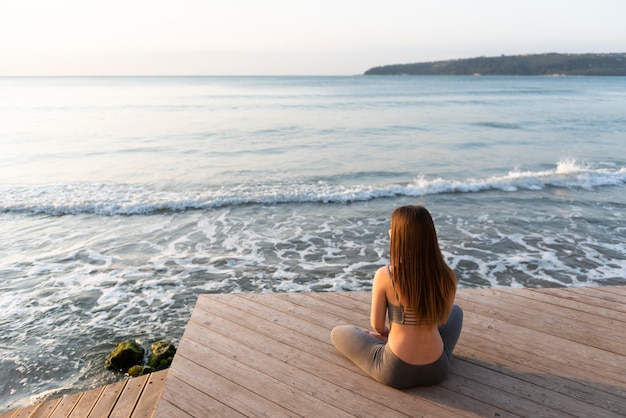 Foto vrouw doet yoga naast de zee