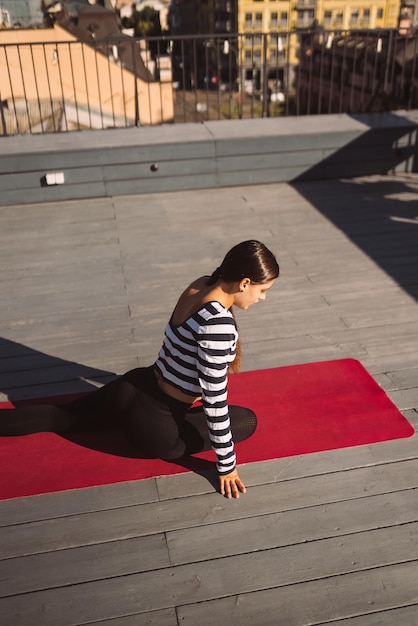 Vrouw doet yoga-oefeningen op het dak van het huis in de vroege ochtend