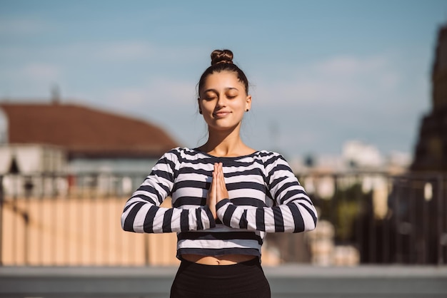 Vrouw doet yoga-oefeningen op het dak van het huis in de vroege ochtend