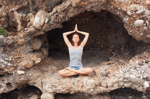 Vrouw doet yoga op de achtergrond van de grot